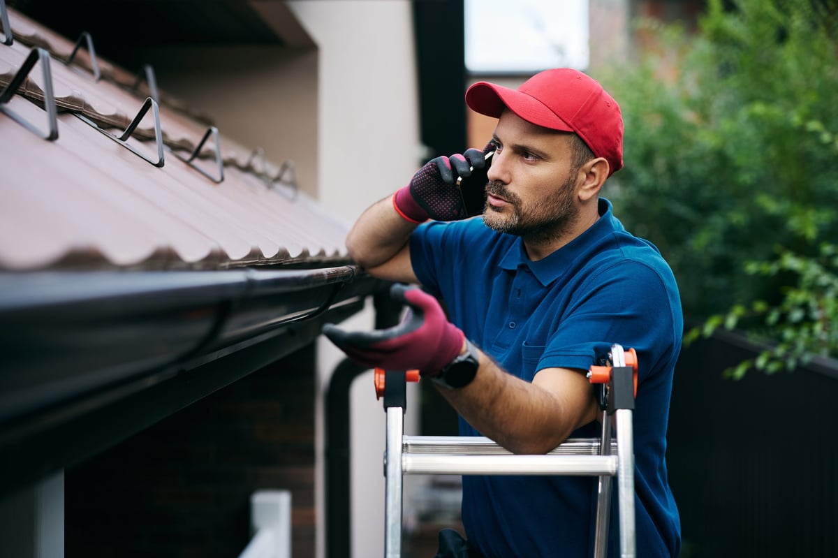 Roofer inspecting a home roof on a ladder